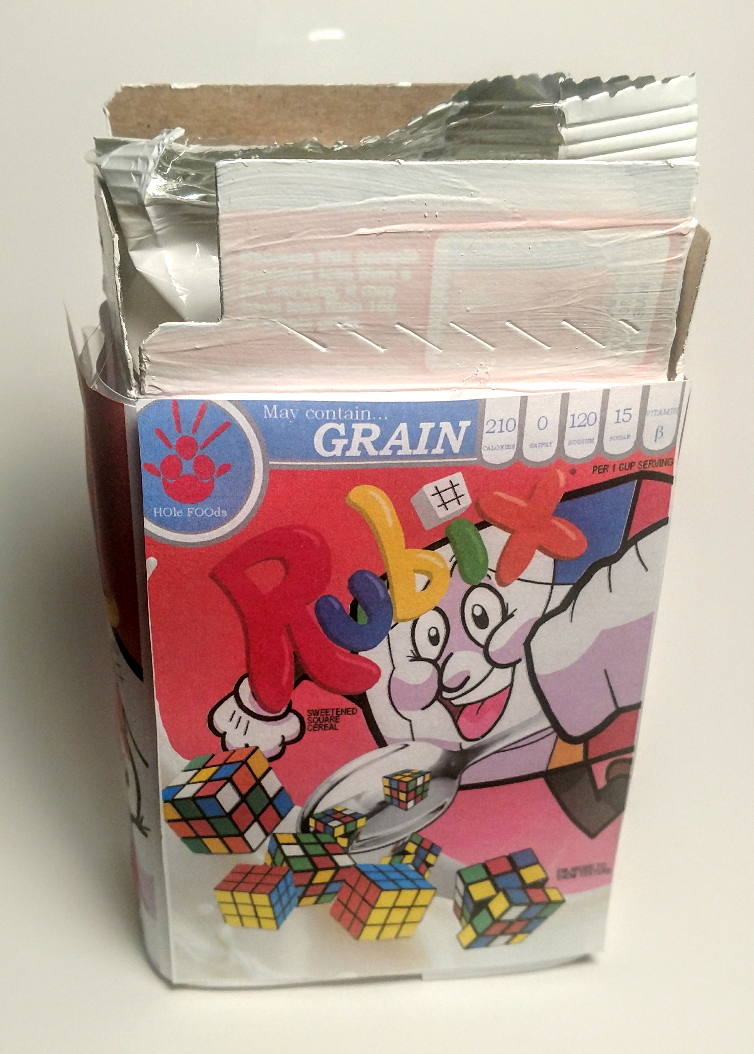 Fake cereal cover for a Rubix-cube themed cereal applied to an actual small cereal box